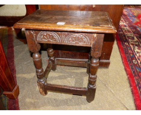 AN ANTIQUE OAK JOINT STOOL WITH CARVED FRIEZE.   W.46cms.