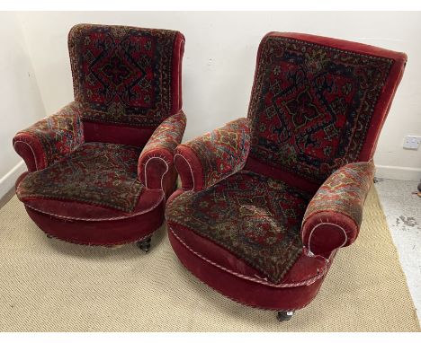 A pair of Victorian scroll armchairs in deep red velvet and carpet type upholstery raised on turned front legs to castors, W 