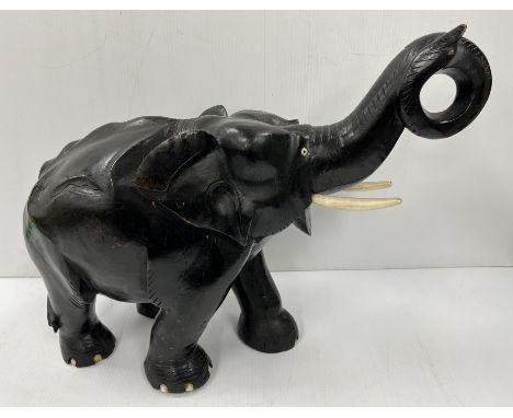 An early to mid 20th Century carved treenware and ebonised elephant figure of large proportions with bone tusk and toenails, 