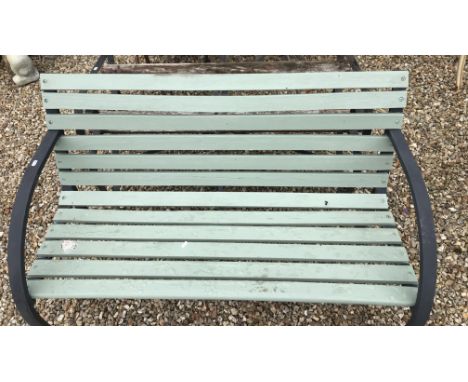 A green painted garden bench together with another unpainted bench, a metal garden table and a small wooden garden table and 