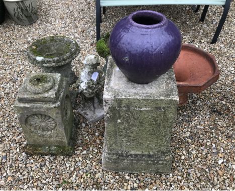 A collection of two concrete garden urns and two concrete plinths with a concrete statue of a child and a small terracotta pl