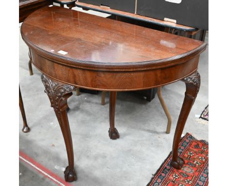 A mahogany demi-lune card table with folding baize-lined top and acanthus carved cabriole supports with ball and claw feet, 9