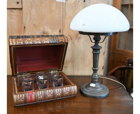 A simulated stack of three leather-bound books, enclosing a set of six shot-glasses, to/w a bronzed table lamp with opaque gl