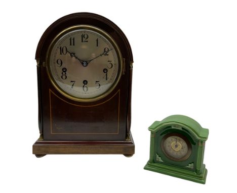 An early 20th century arch topped mahogany mantle clock with inlaid satinwood stringing on a moulded plinth with four turned 