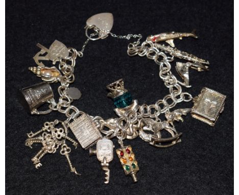A silver charm bracelet, suspending fifteen assorted charms inc Shark, Tankard, Keys, Cine Camera, Gnome, Rocking Horse etc, 