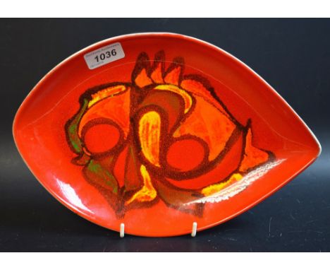 A Poole Delphis arrow head plate, decorated by Anne Godfrey, applied with a stylised fish motif, in bright red and orange ton