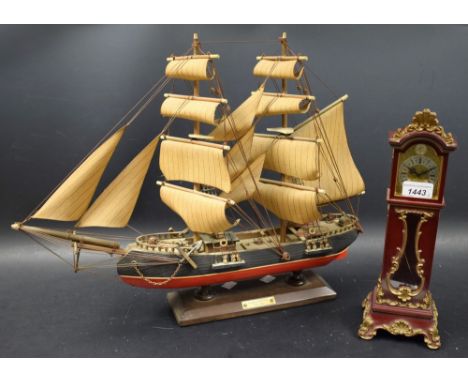 A desk top miniature longcase clock, Schmidt, gilt dial, gilt and red case; a wooden model ship Bergan tin (2)