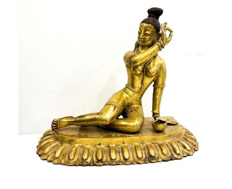 Tibet or Nepal finely cast and chased gilt bronze reclining female figure, beside a kapala, on plinth
