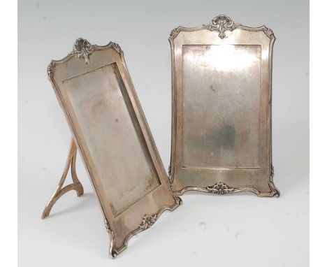 A pair of Mappin &amp; Webb silver easel photograph frames, having shell cast tops, the whole being silver and on silver ease