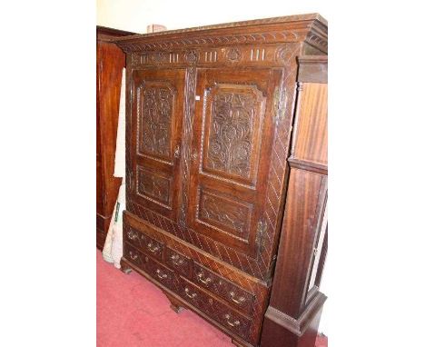 An 18th century joined oak livery cupboard, having twin blind carved panelled doors, opening to reveal unfitted interior, the