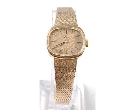 A lady's 9ct yellow gold Omega manual wind wristwatch, featuring a cushion shaped textured champagne baton dial, attached to 