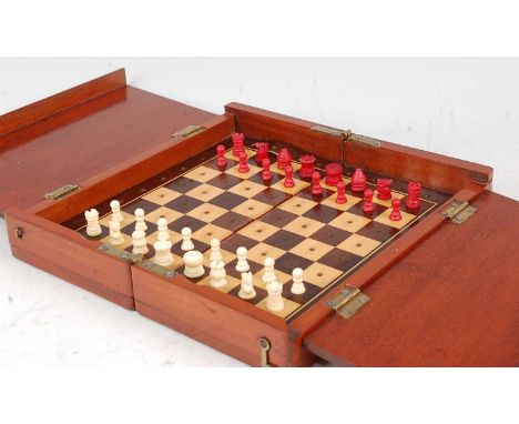 A circa 1900 mahogany travelling chess set, having fold-out action opening to reveal rosewood and satinwood veneered playing 