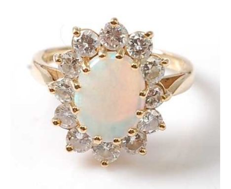 An 18ct yellow and white gold, opal and diamond oval cluster ring, featuring a centre cabochon cut opal within a border of 12