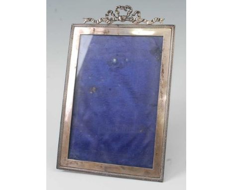 An Edwardian silver photograph frame, having ribbon surmount, engine turned border, and velvet bound easel arm, maker Stokes 
