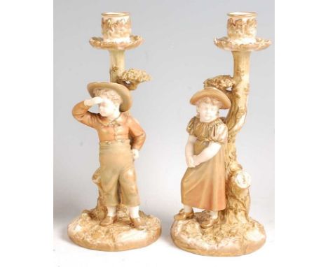 A pair of Hadley Worcester porcelain boy and girl candlestick figures, heightened in gilt, impressed and printed puce backsta