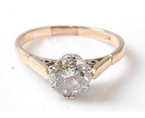 A yellow and white metal diamond single stone ring, featuring a round brilliant cut diamond in a fancy scroll work collet set