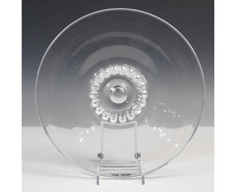 A clear round serving tray featuring a smooth flat surface with a wide rim. The design centers around a polished bubble motif