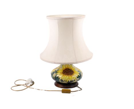 A contemporary Moorcroft pottery lamp with sunflower decoration. Raised on a circular wooden base. H21cm