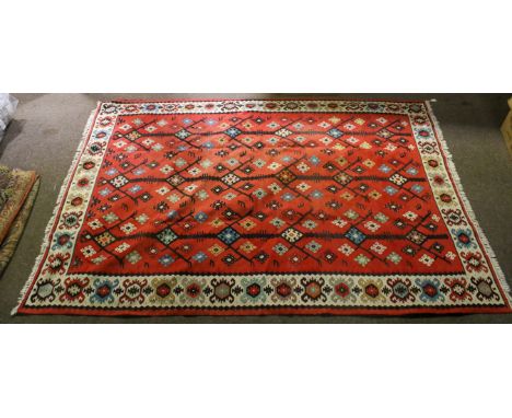 A 20th century woven Aztec style rug. Having a geometric pattern on a red ground, within cream, blue and black borders, white