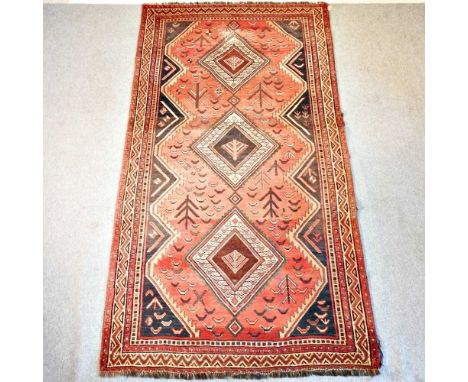 A Persian woollen carpet, with three central diamonds, on a red ground, 296 x 158cm