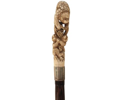 AN EARLY 20TH CENTURY WALKING CANE, the Japanese Meiji period ivory handle carved as a climbing monkey feeding two baby monke