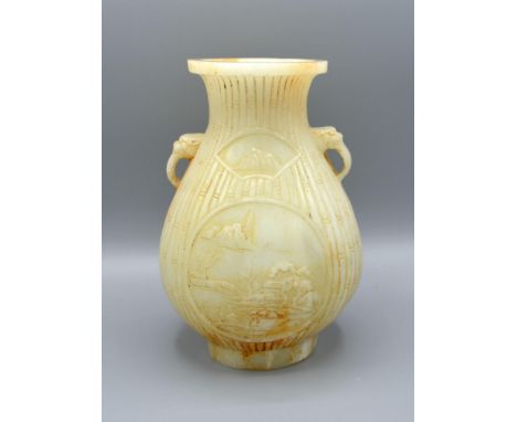 A Chinese Jade Vase carved with two reserves amongst bamboo and with foe head side handles, 19 cms tall 