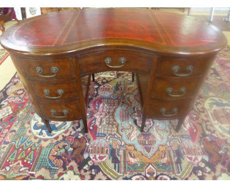A mahogany kidney shaped seven drawer desk with a leather inset top 1.38m wide x 80cm deep x 77cm tall - light surface scratc