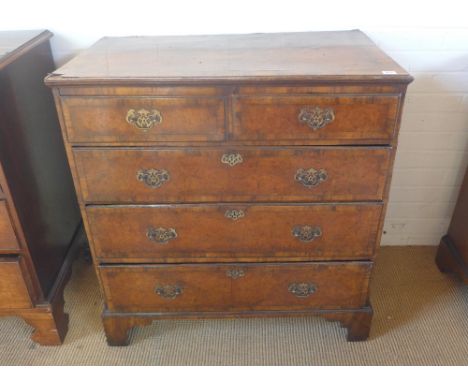 A Georgian walnut veneered chest of two short over three long graduated drawers raised on bracket supports with brass handles