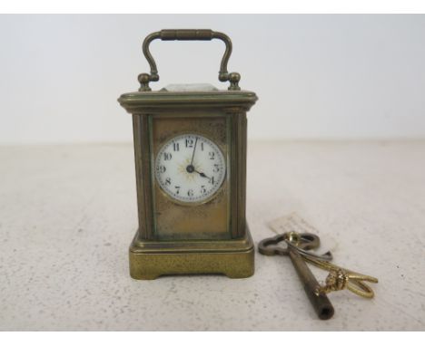 A brass cased carriage clock of small proportions - Arabic Numerals to the white enamel dial, bevelled glass to top front, ba