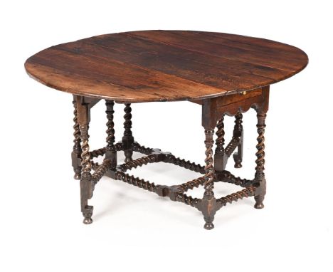 A LARGE OAK GATELEG DINING TABLE FIRST HALF 18TH CENTURY On 'barley twist' gateleg supports 75cm high, 154cm (open), 136cm de