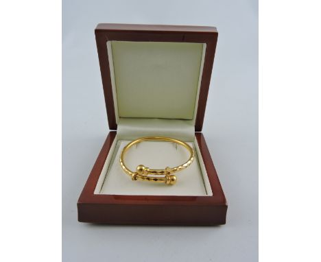 A yellow metal child's torque bangle, with bright-cut facets, 8.5g.