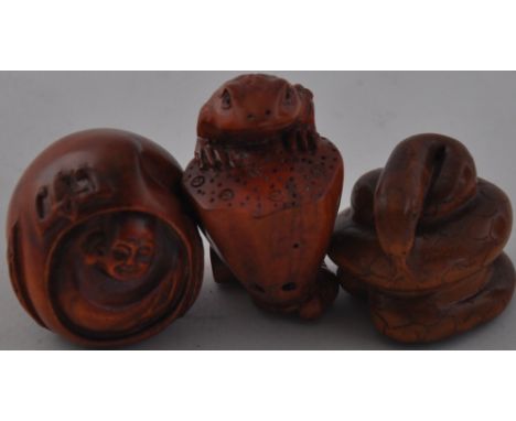 Three Japanese harwood netsukes in the form of a snake, frog and Buddha. 