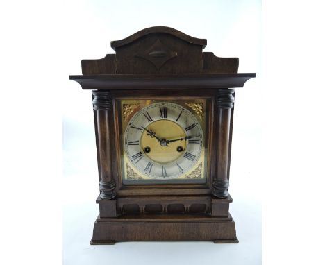 An early 20th century German mantle clock, the walnut case with columns flanking a brass dial and silvered chapter ring set o