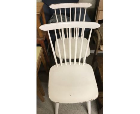 A pair of vintage wooden stick back kitchen chairs painted white.  