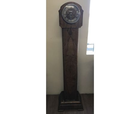 An Art Deco walnut veneer granddaughter clock. Complete with key and pendulum. Spring to pendulum broken but mechanism is in 