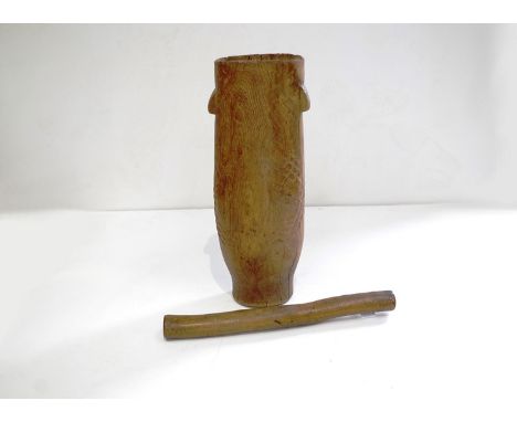 A hollowed tree trunk mortar with carved lug handles and scale decoration and a wooden stick pestle (2) 