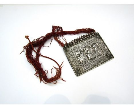 A North African white metal panel of horizontal rectangular form, chased with three figures within an arcaded and multi-strip