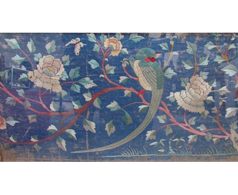 A 19th Century Chinese blue ground silk embroidered panel depicting birds perched in flowering branches. 34 x 131cm worn