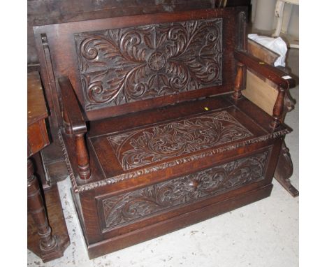Stained oak, foliate carved Monks bench on a platform base.