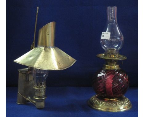 Brass single burner oil lamp with ruby glass wrythen globular reservoir on repousse brass base, clear chimney together with a