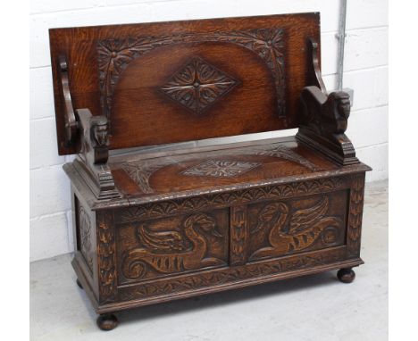 An early-to-mid 20th century oak monks' bench or box settle, the pivoting top panel carved with acanthus and supported on sty