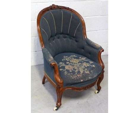 A Victorian walnut nursing chair with blue floral tapestry upholstery, curved support and castors. 