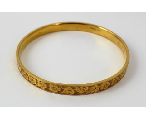 A 9ct yellow gold floral engraved bangle, diameter 9cm, approx 11.8g.