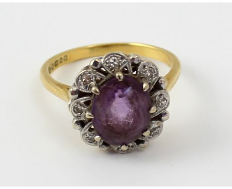 An 18ct gold ladies' dress ring set with central oval amethyst and small diamond chip surround, size O, approx 4.7g.