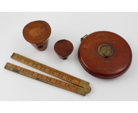 A vintage tape measure, two leather-cased hunt cups and a folding rule (4).