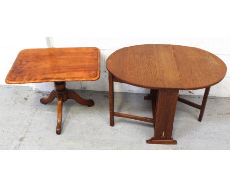 An oak circular drop-leaf table of small proportions on gate-leg support and small side table on central column to trefoil su