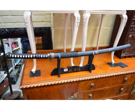 A reproduction Japanese Katana and scabbard, on wooden stand. 