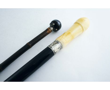 A LATE 19TH / EARLY 20TH CENTURY WALKING CANE with a thick ebonised shaft, a horn tip &amp; a silver ferrule, the turned ivor