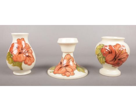 Three pieces of Moorcroft pottery. To include two small vases and candlestick decorated in the Coral Hibiscus pattern. All st