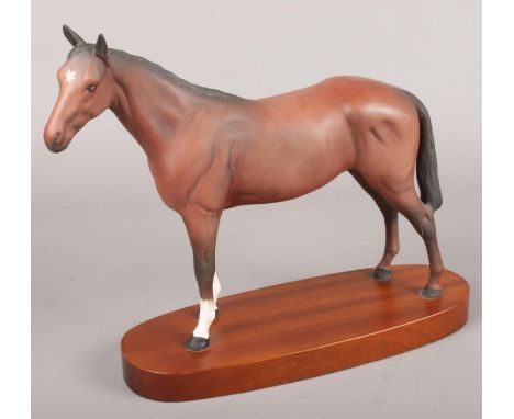 A ceramic Royal Doulton horse on wooden plinth. (23cm tall)  